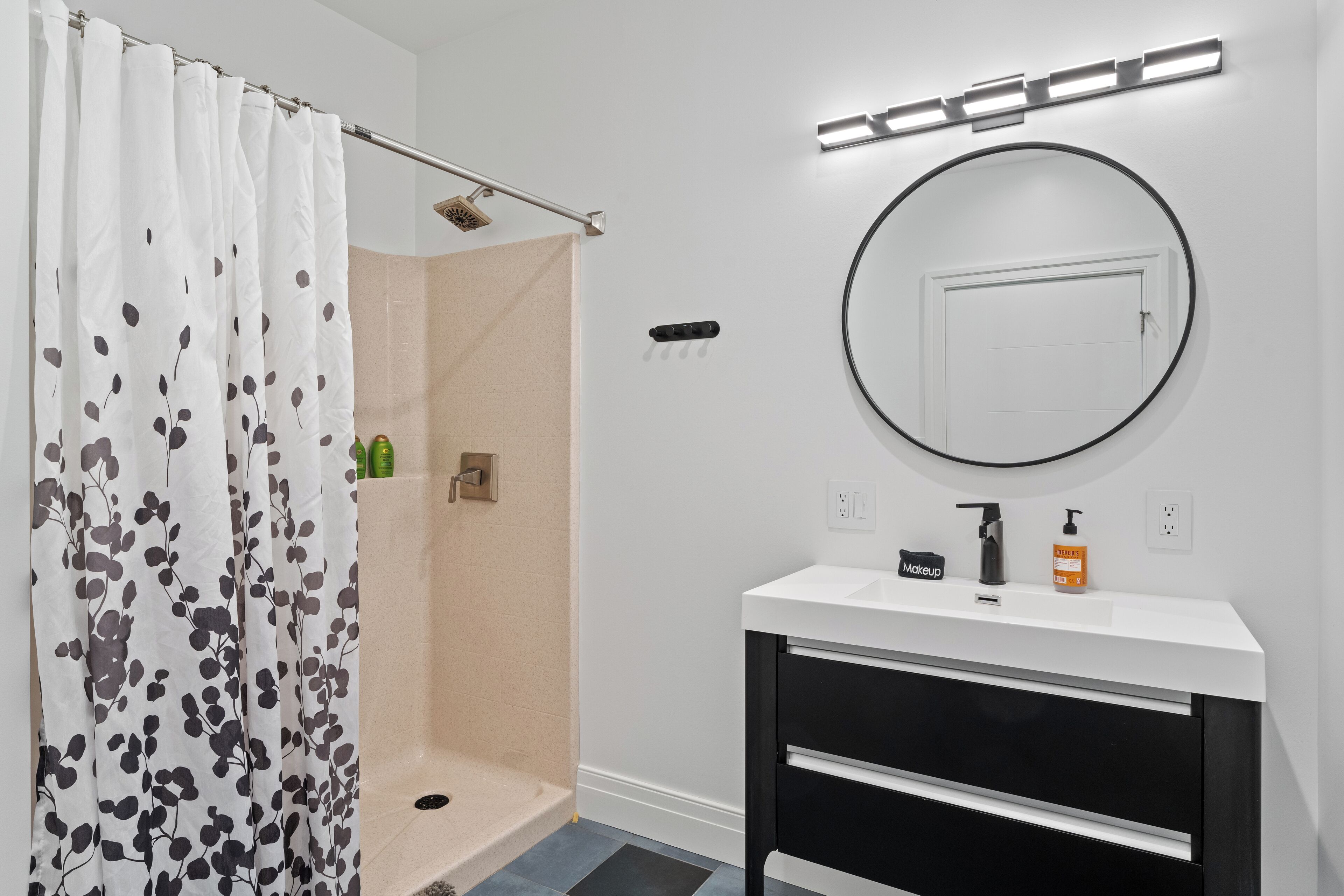 A bathroom with a shower, a sink with a mirror, and toiletries on the counter.
