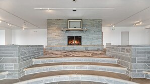 A modern interior with a stone fireplace, built-in shelves, and a staircase leading to an upper level.