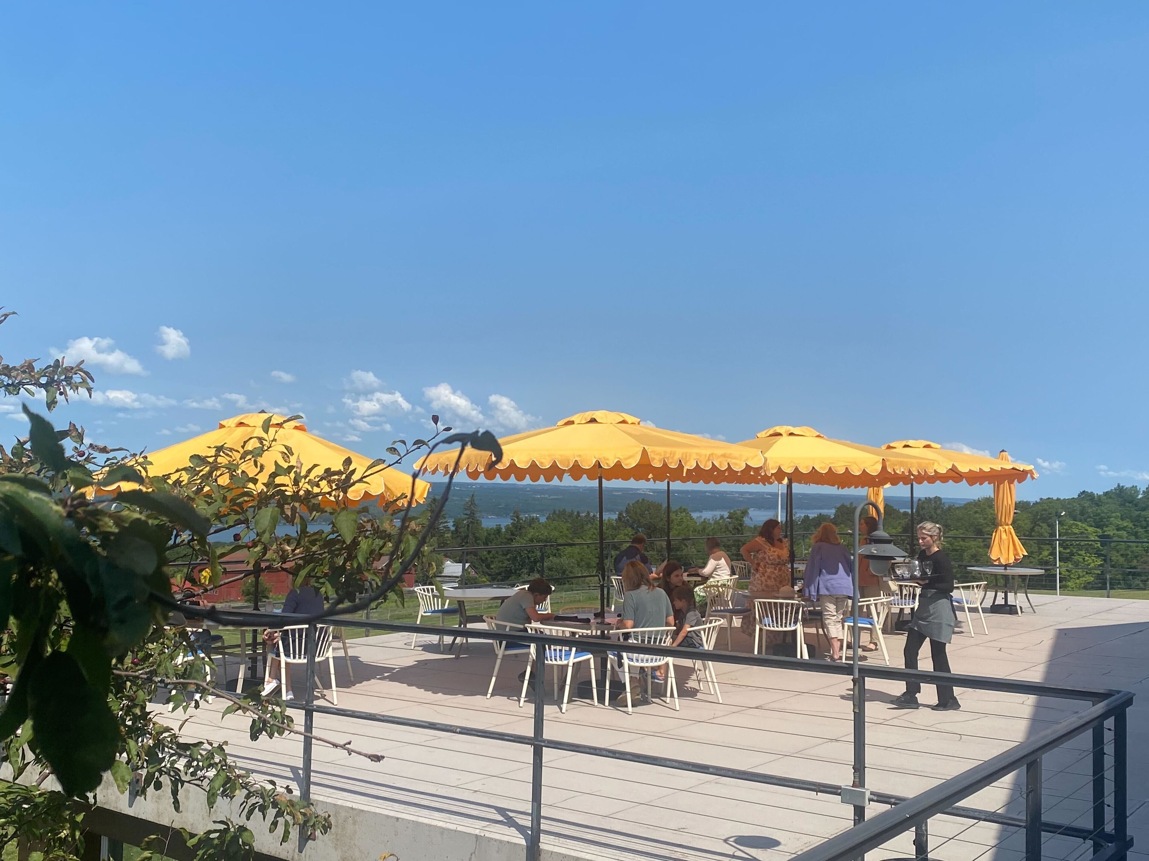 Un espace extérieur aménagé avec des parasols jaunes, des chaises blanches et des tables.