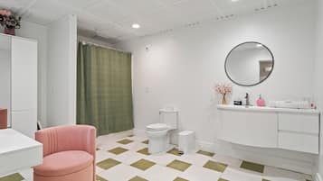 Un baño moderno con inodoro blanco, lavamanos y espejo.