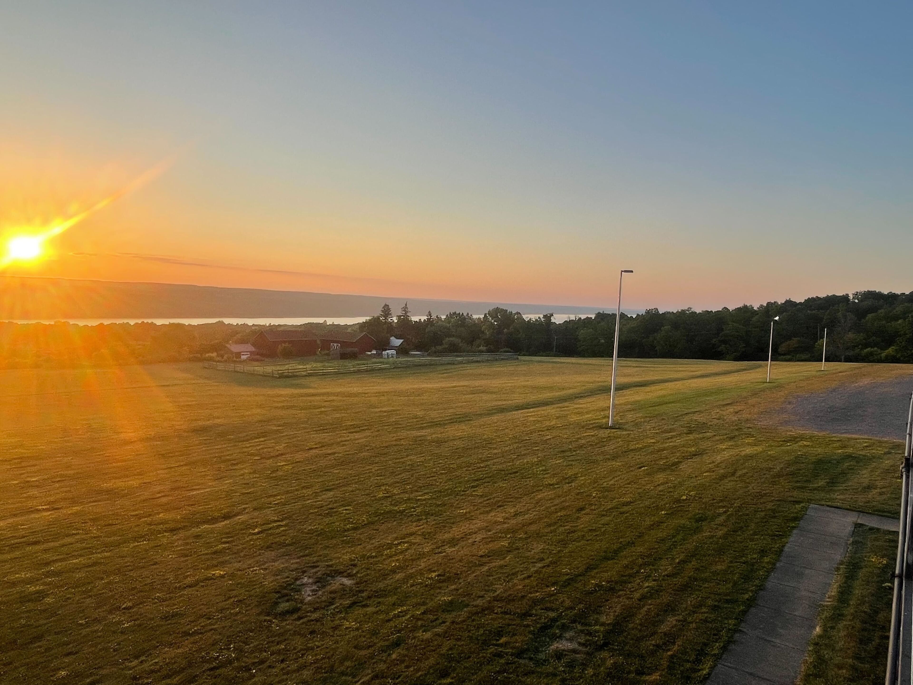 Un parcours de golf offrant une vue dégagée sur le coucher de soleil, un sentier pédestre et un plan d'eau situé au loin.
