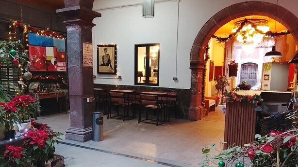 Un espacio interior con zona de estar, una columna y un acceso a otra habitación.