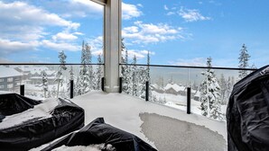 A balcony with a view of a snowy landscape, a concrete pillar, and black outdoor cushions. - Western Star Chalet- Ski-in/out & Amazing Mtn View (Big White)