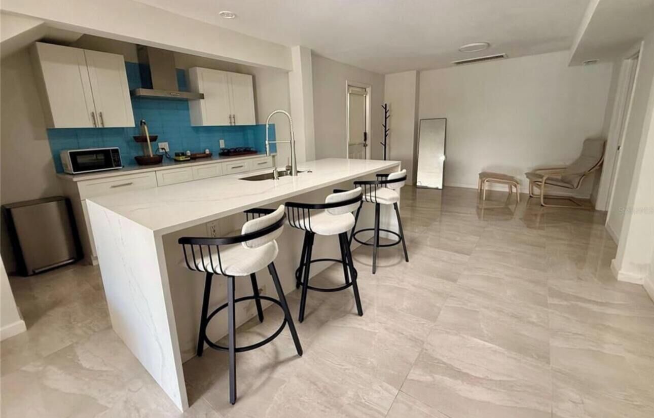 Une cuisine moderne dotée d’un îlot central, de tabourets de bar et d’un coin repas avec des chaises.