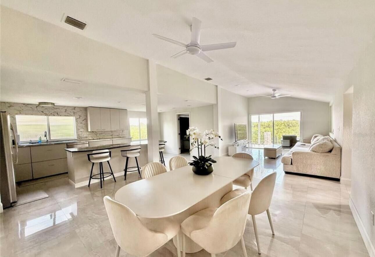 Een ruime, moderne keuken met een groot eiland, witte kasten en uitzicht op de omgeving.