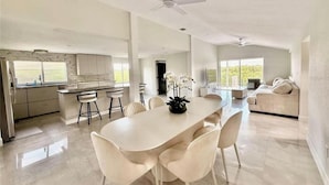 Un'ampia cucina moderna con una grande isola, mobili bianchi e vista sull'esterno.