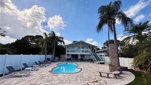 Area piscina con sedie a sdraio, una piccola piscina e una casa a due piani con una scala che conduce al livello superiore.