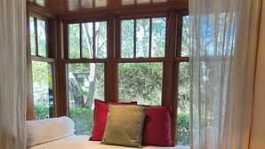 Una habitación acogedora con una cama cerca de una ventana, un banco de madera y un tapete estampado.