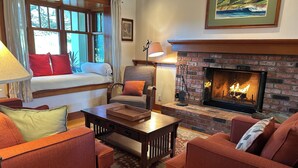 Una sala de estar acogedora con chimenea, un sofá, un sillón y una mesa.
