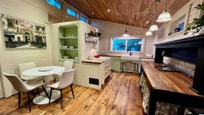 A compact kitchen with a dining area, wooden floors, and a window providing natural light. - 2-bedroom house walking distance to downtown Grand Haven (Grand Haven)