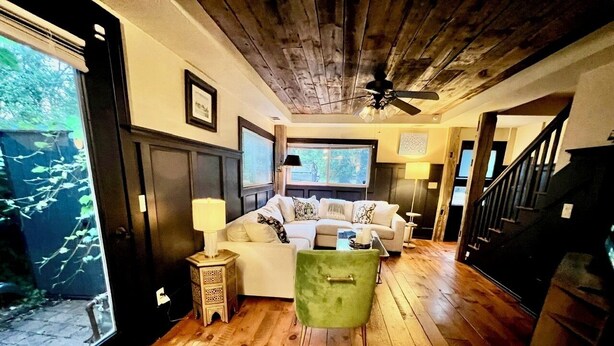 A cozy living room with wooden flooring, a green chair, a white sofa, and a staircase leading to another level. - 2-bedroom house walking distance to downtown Grand Haven (Grand Haven)