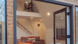 Een modern interieur met een houten gevel, een trap, een bank, een stoel en een klein tafeltje.