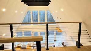 Een modern interieur met een houten vloer, zwarte metalen leuning en een uitzicht op het exterieur door grote ramen.