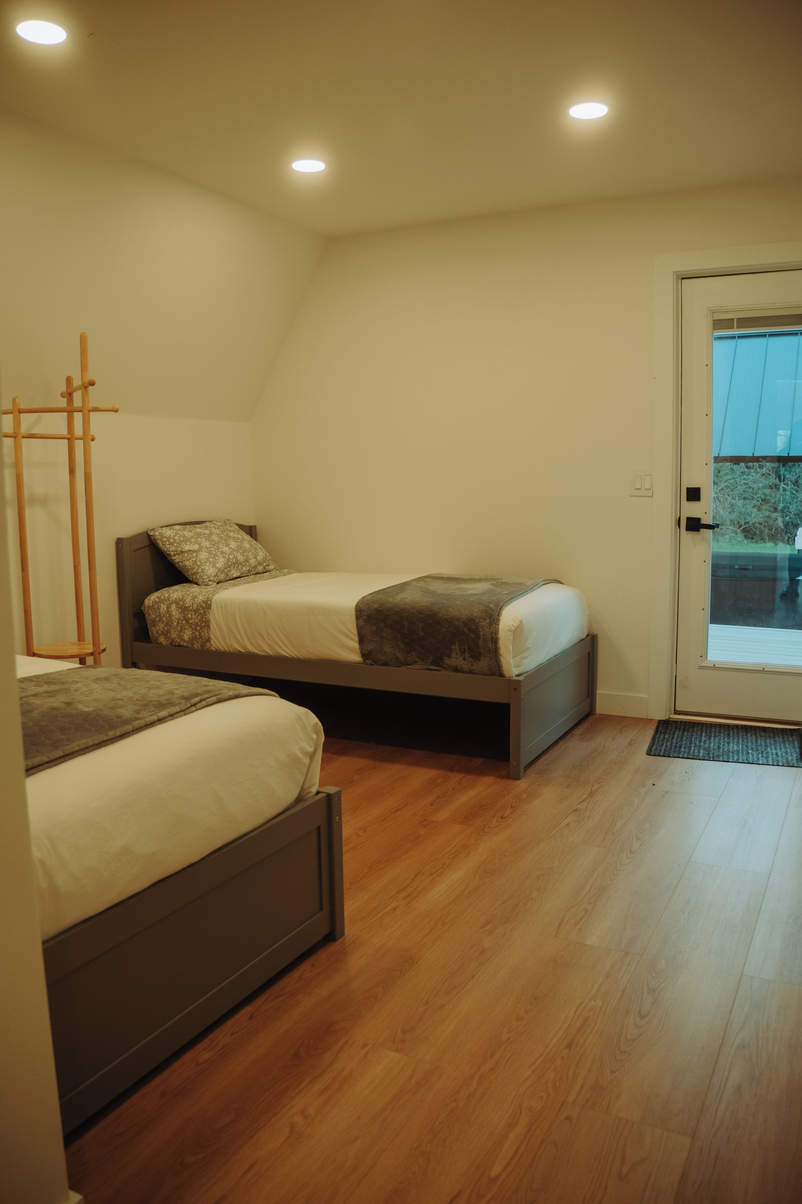 Un dormitorio con dos camas, una escalera de madera y una puerta que da al exterior.