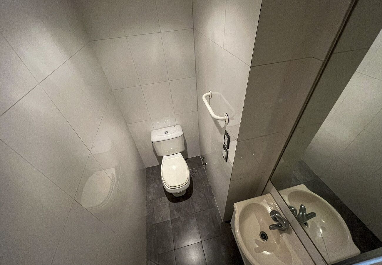 Un baño pequeño con inodoro, lavamanos y espejo.