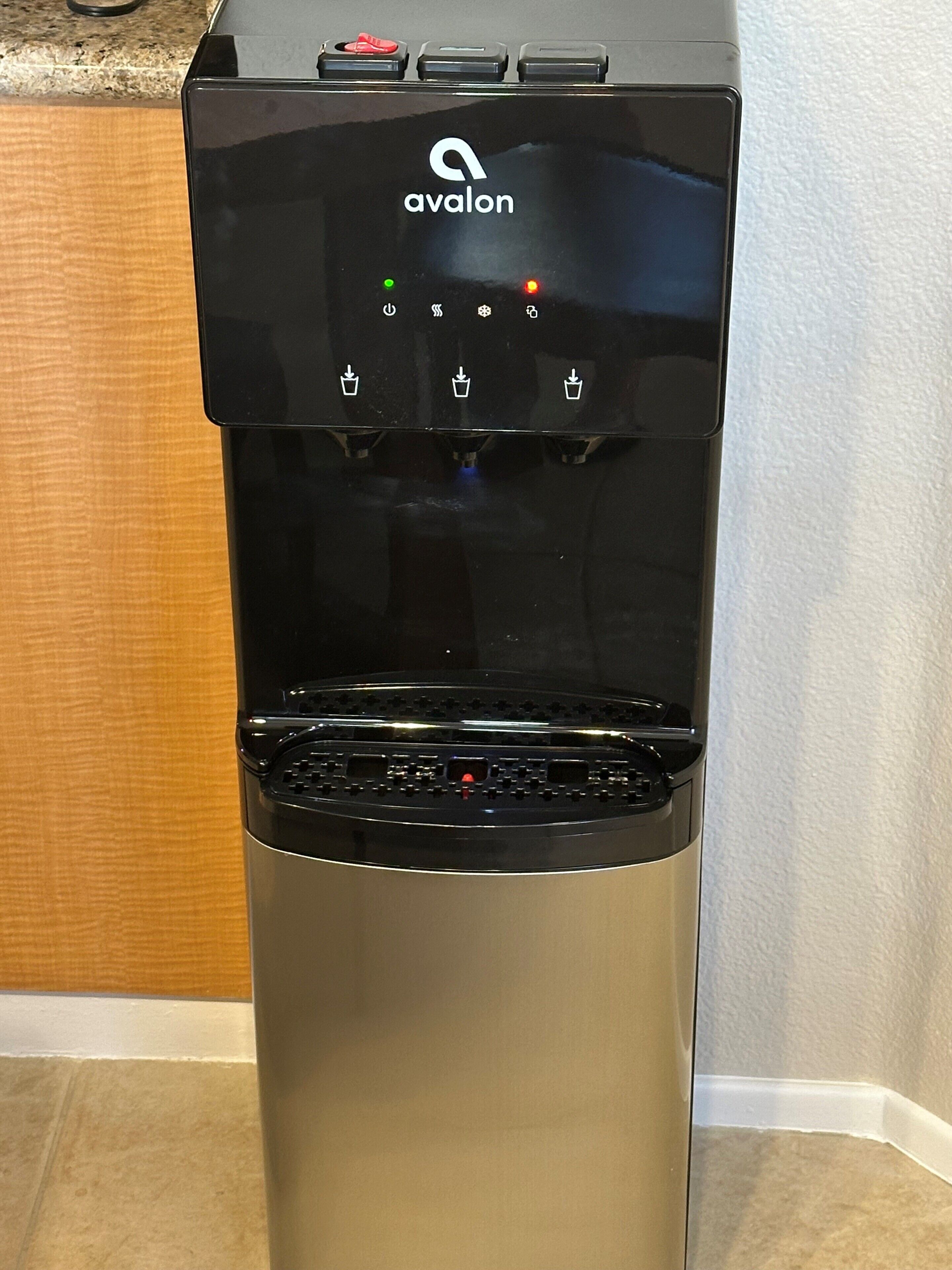 En vattenautomat i rostfritt stål med ett varumärkeslogotyp, flera olika alternativ för vattenutgivning och en kontrollpanel.