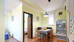 A dining area with a table, chairs, and a shelf with dishes. - Holiday apartment with air conditioning (Pula)