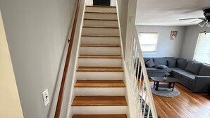 Una escalera de madera con barandillas blancas que conduce a una puerta oscura.