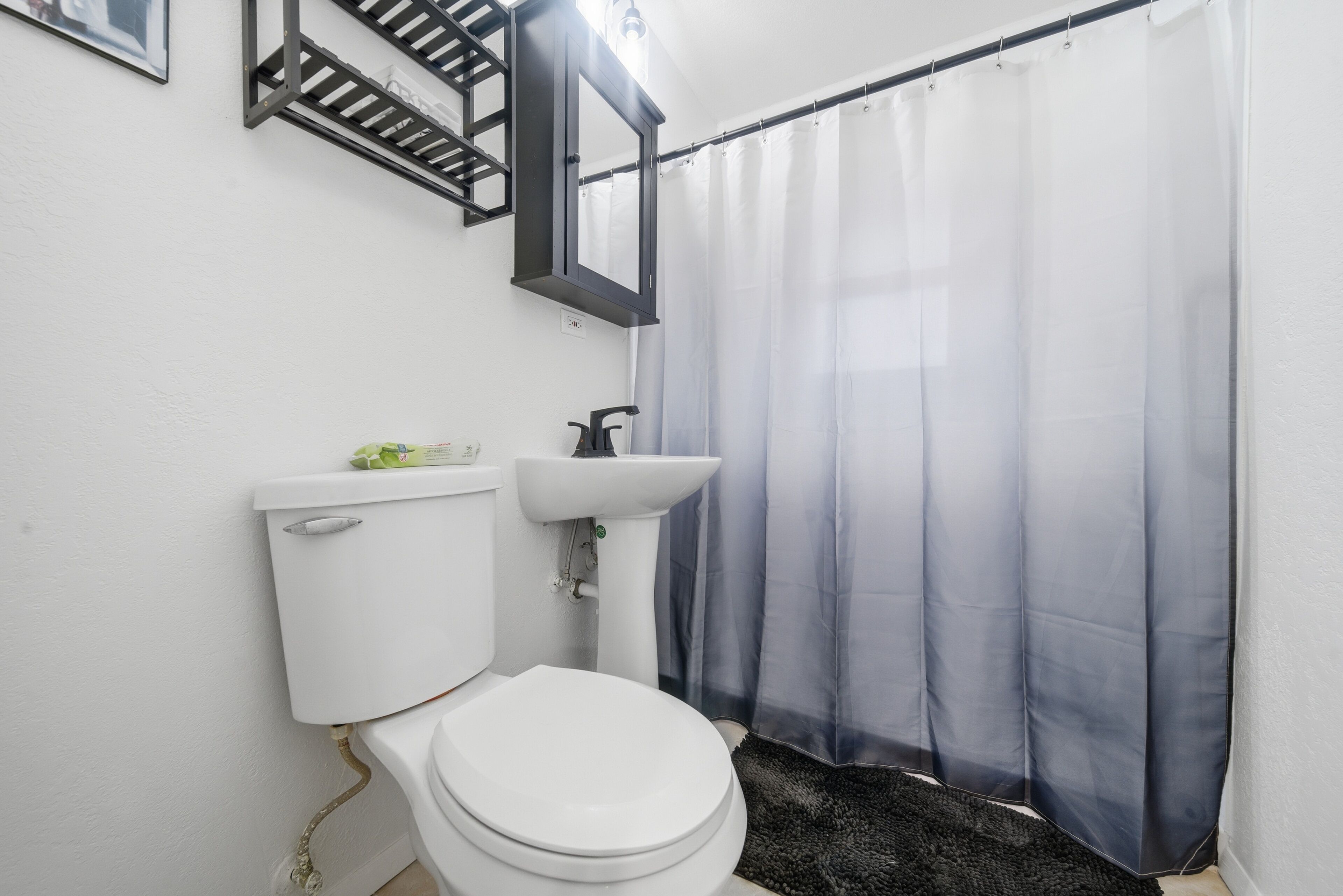 Un baño con inodoro, lavamanos y cortina de ducha.