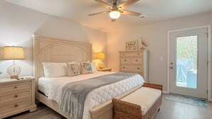 A bedroom with a bed, nightstands, a ceiling fan, a dresser, and a door with a view. - Updated 3BR Beach House • 3 Blocks to Ocean • Fenced Yard • Grill (North Myrtle Beach)