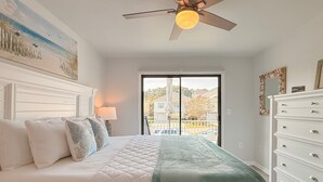 A bedroom with a bed, a ceiling fan, a dresser, and a view of the outside. - Updated 3BR Beach House • 3 Blocks to Ocean • Fenced Yard • Grill (North Myrtle Beach)