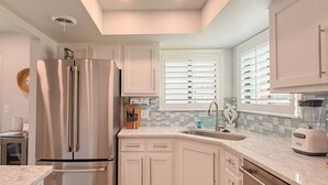 A modern kitchen with white cabinetry, stainless steel appliances, a granite countertop, and a window with blinds. - Updated 3BR Beach House • 3 Blocks to Ocean • Fenced Yard • Grill (North Myrtle Beach)