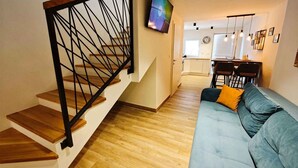 Een modern interieur met een trap, een zithoek met een bank, een eethoek en een keuken.