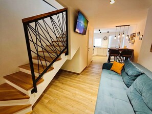 A modern interior with a staircase, a living area with a sofa, a dining area, and a kitchen. - Holiday home with terrace and two bedrooms (Jadranovo)