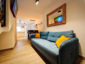 A living room with a sofa, a dining table, and a TV mounted on the wall. - Holiday home with terrace and two bedrooms (Jadranovo)