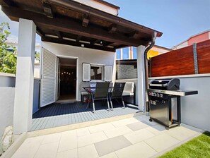 An outdoor patio with a grill, seating area, and a door leading to an interior space. - Holiday home with terrace and two bedrooms (Jadranovo)