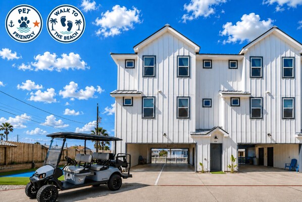 A two-story building with a white exterior, multiple windows, and a gated entrance. - Rooftop Ocean View + Pool + Golf Cart (Port Aransas)