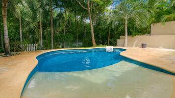 Een buitenzwembad, parasols bij het zwembad en ligstoelen