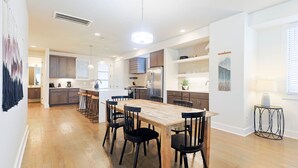 A spacious kitchen with a central island, wooden dining table, and bar stools. - 5 Points East Nashville Luxury | 2 King Suites, Wet Bar & Dual Decks | Sleeps 12 (Nashville)