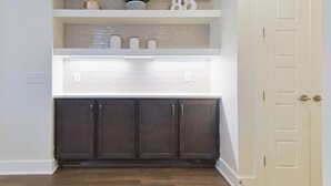 A kitchen with dark wooden cabinets, white upper cabinets, and a white tiled backsplash. - 5 Points East Nashville Luxury | 2 King Suites, Wet Bar & Dual Decks | Sleeps 12 (Nashville)
