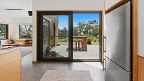 A modern kitchen with a sliding glass door leading to an outdoor patio. - Tranquility Base - 1 Bedroom Unit - Beachside (Coningham)