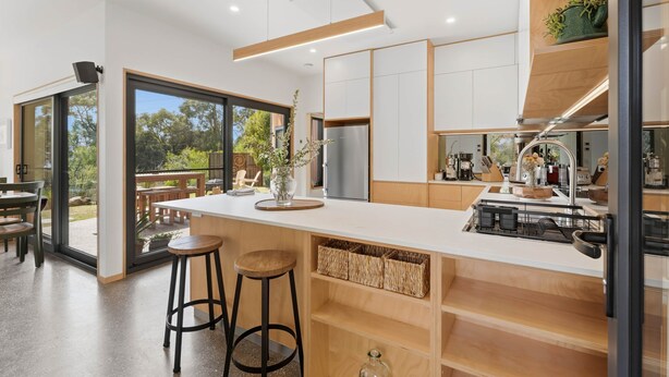 A modern kitchen with a large island, bar stools, and a view of the outdoors. - Tranquility Base - 1 Bedroom Unit - Beachside (Coningham)