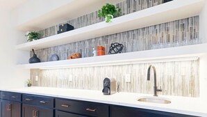 A modern kitchen with dark cabinets, a white countertop, and a tiled backsplash.