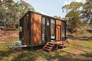 A compact wooden cabin with a small porch, a bed, and a grill. - Maroota Greens by Tiny Away (Maroota)