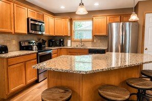 Eine Küche mit Holzschränken, Edelstahlgeräten, Granit Arbeitsplatten und einer Bar mit Hockern.
