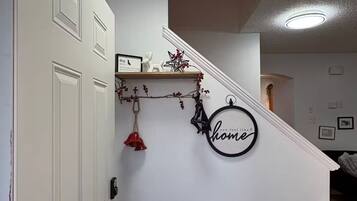 A staircase with a white wall, a small shelf with decorative items, and a circular sign with the word "home".