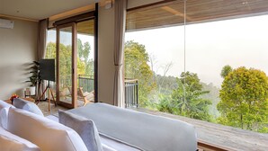 Une chambre avec une grande fenêtre, un lit, une chaise et une petite table.