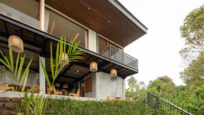 Une maison moderne dotée d’un balcon, de grandes fenêtres et d’un espace salon extérieur.