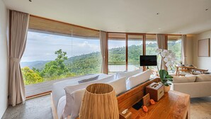 Une chambre moderne dotée d’une grande fenêtre offrant une vue panoramique sur un paysage boisé.