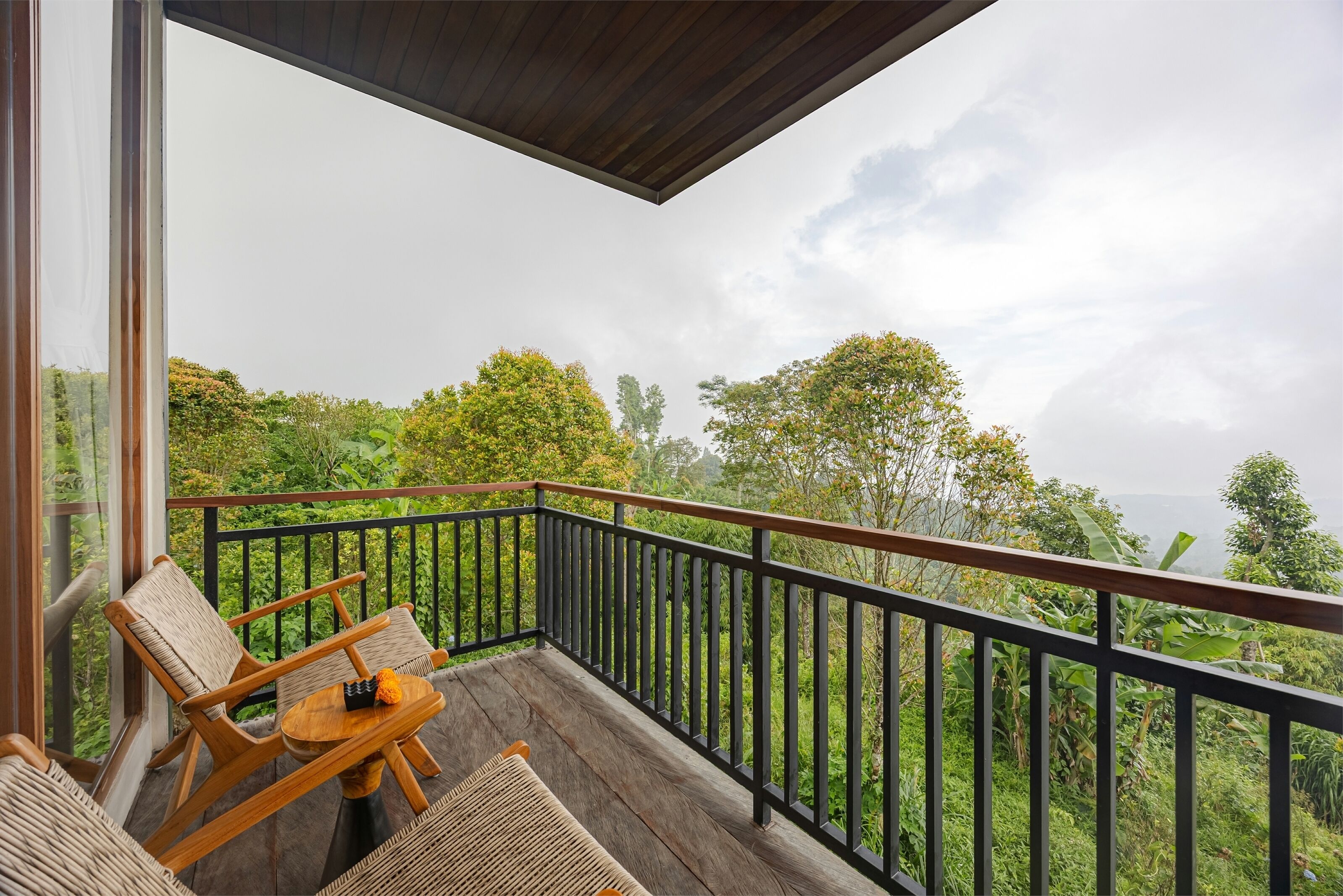 A balcony with wicker furniture and a view of lush greenery.