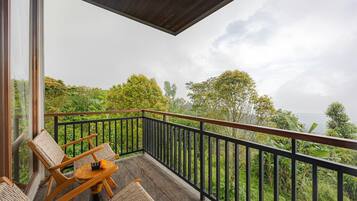 A balcony with wicker furniture and a view of lush greenery.