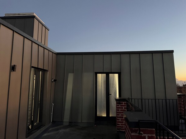 A modern building with a flat roof, a large sliding glass door, and a brick staircase.
