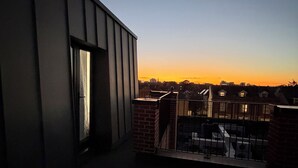 Eine Dachterrasse mit Blick auf die städtische Skyline bei Sonnenuntergang.
