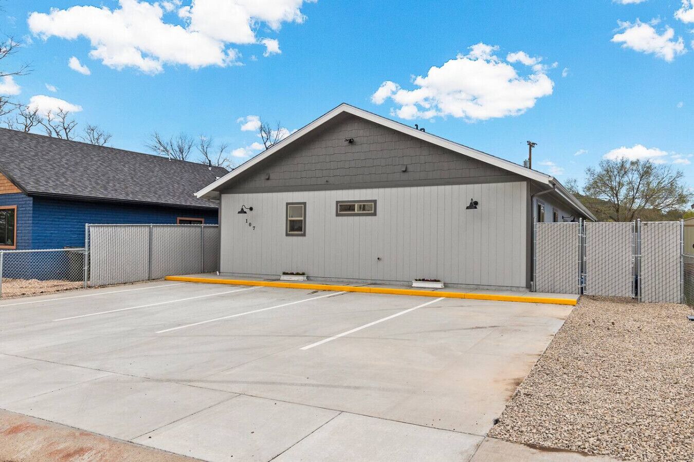 A building with a garage, a fenced parking area, and a clear sky.