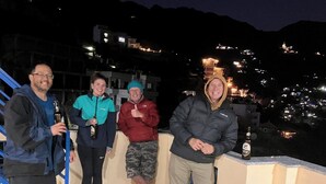 Un grupo de personas en un balcón con vistas a una zona montañosa de noche.