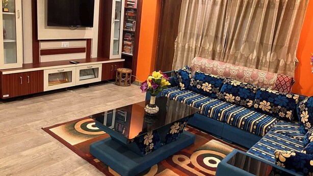 Una sala de estar con un sofá, una mesa de centro, un televisor y una estantería.